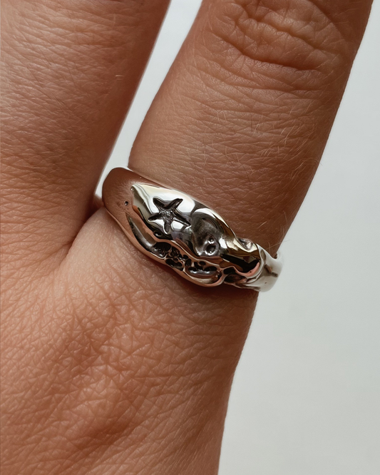 Silver ring on a finger against a neutral background