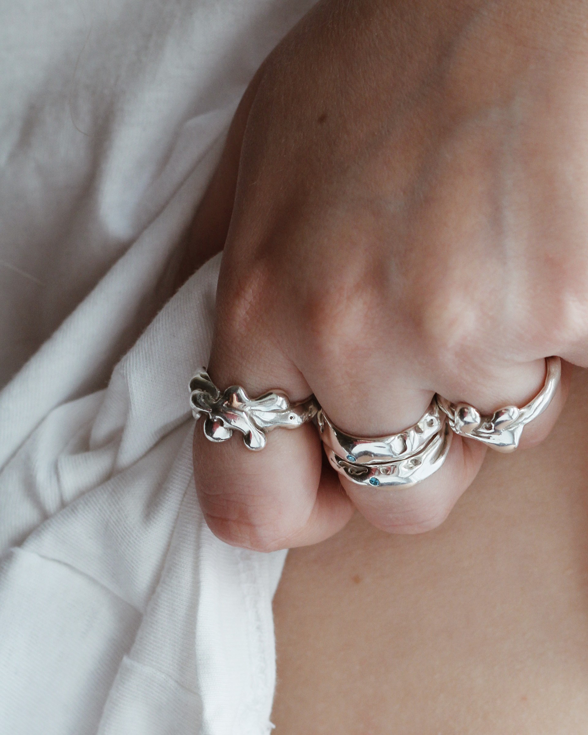 Close-up of a hand wearing silver rings on a light background