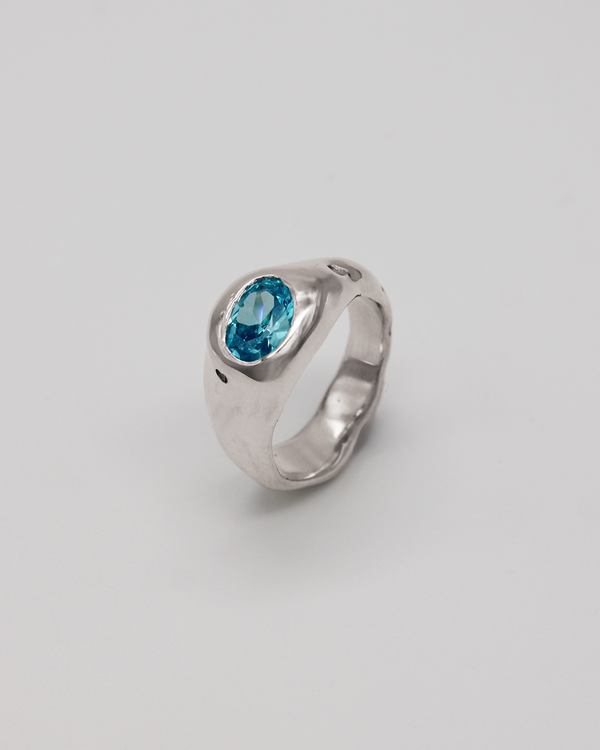Silver ring with a blue stone on a plain background
