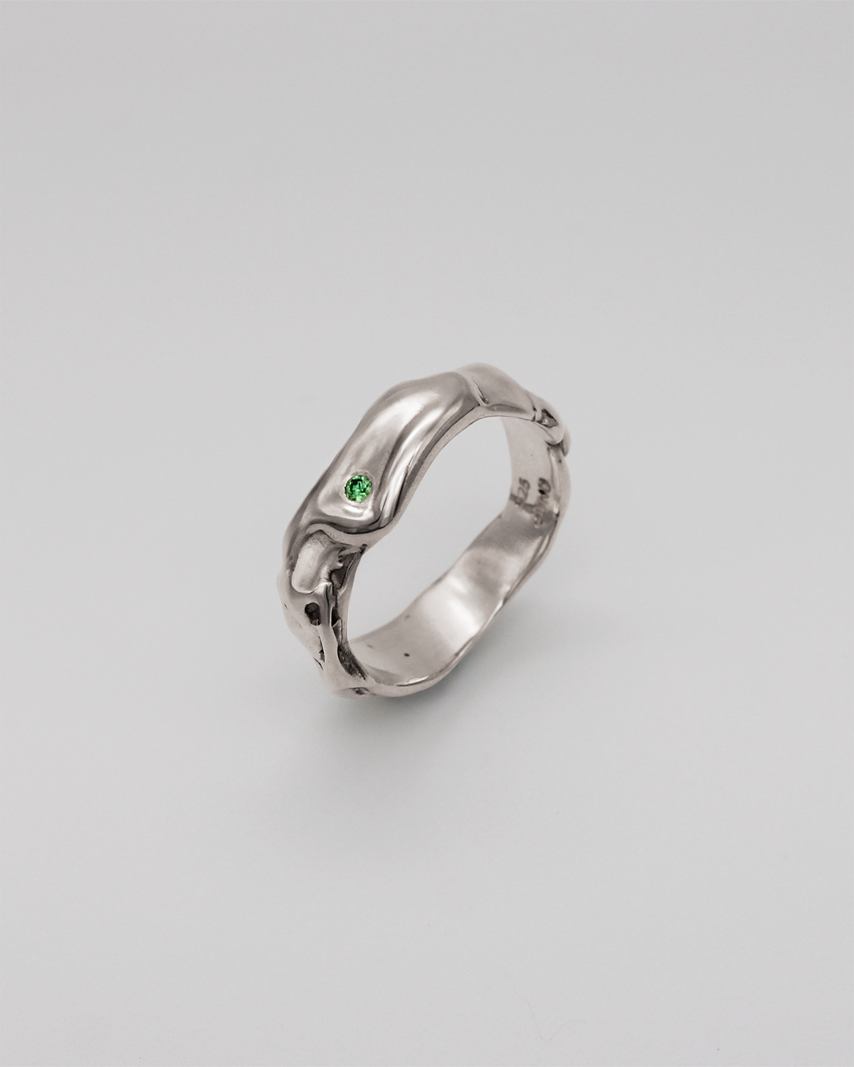 Silver ring with a green stone on a light gray background