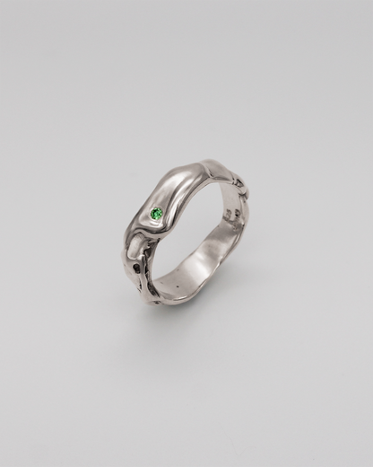 Silver ring with a green stone on a light gray background