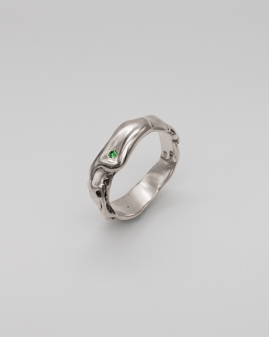 Silver ring with a green stone on a light gray background