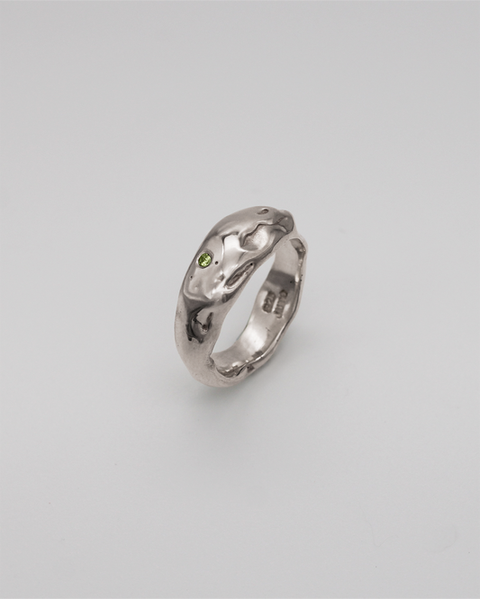 Silver ring with a green stone on a light gray background