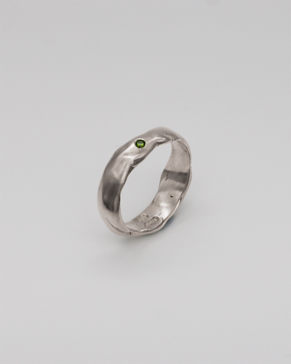 Silver ring with a green stone on a light gray background