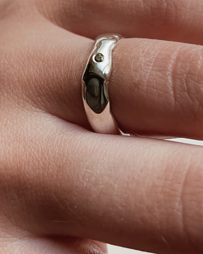Silver ring with a small green stone on a finger