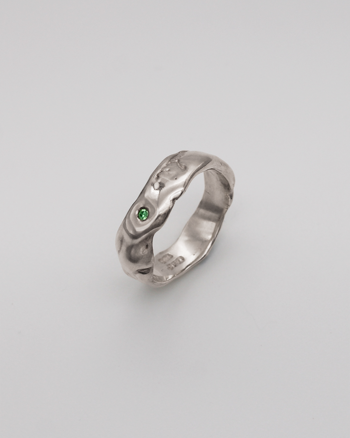 Silver ring with a green stone on a light gray background