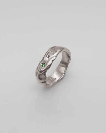 Silver ring with a green stone on a light gray background