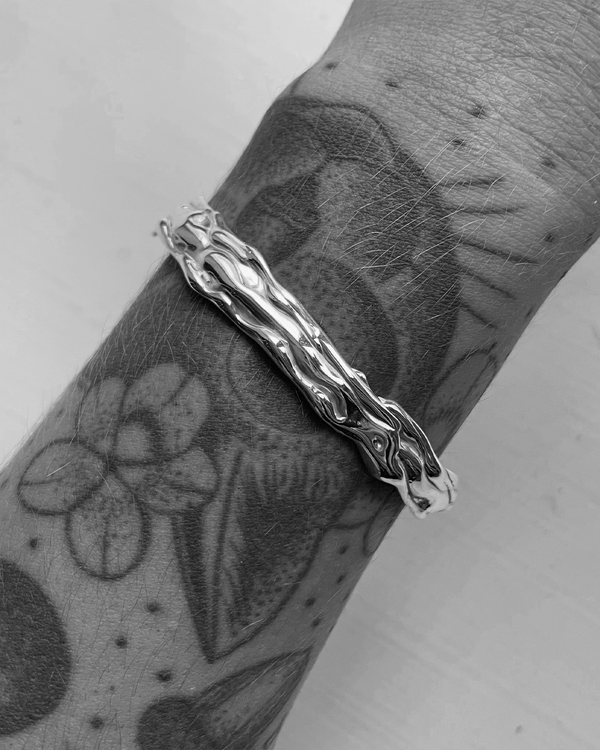 Silver bracelet on a wrist with tattoos