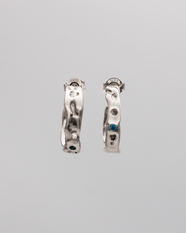 Pair of silver hoop earrings with stones on a gray background