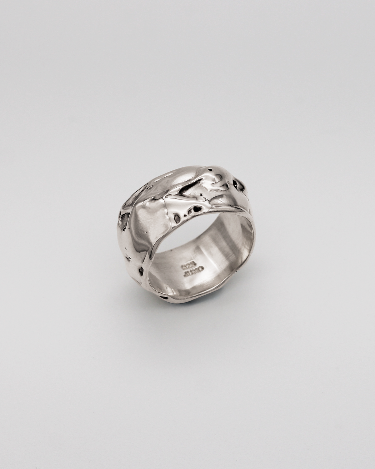 Silver ring with a textured design on a light gray background