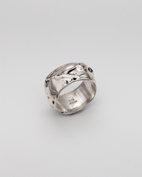 Silver ring with a textured design on a light gray background