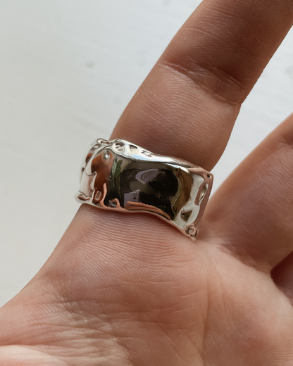 Silver ring on a finger against a neutral background