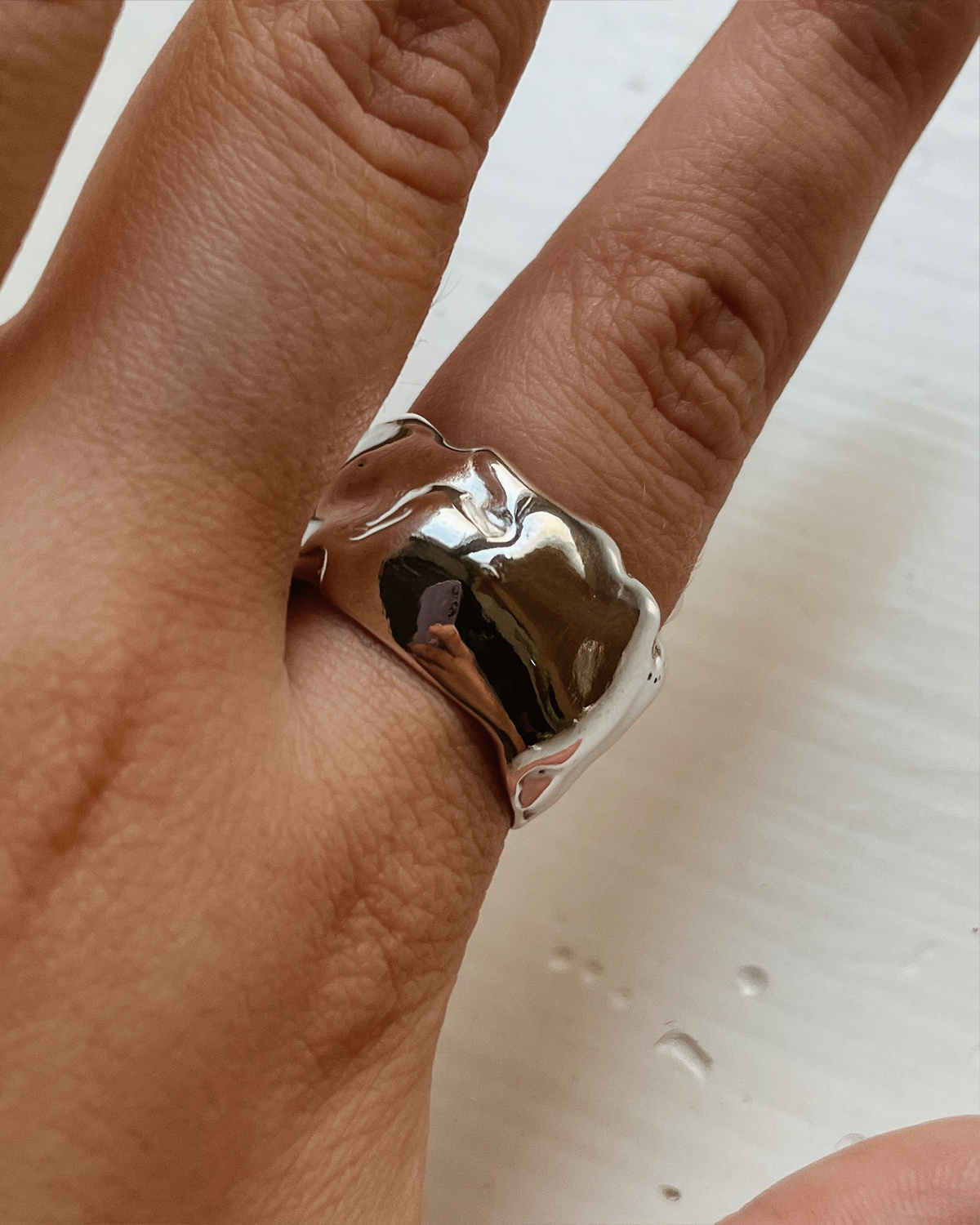 Silver ring on a finger with a plain background