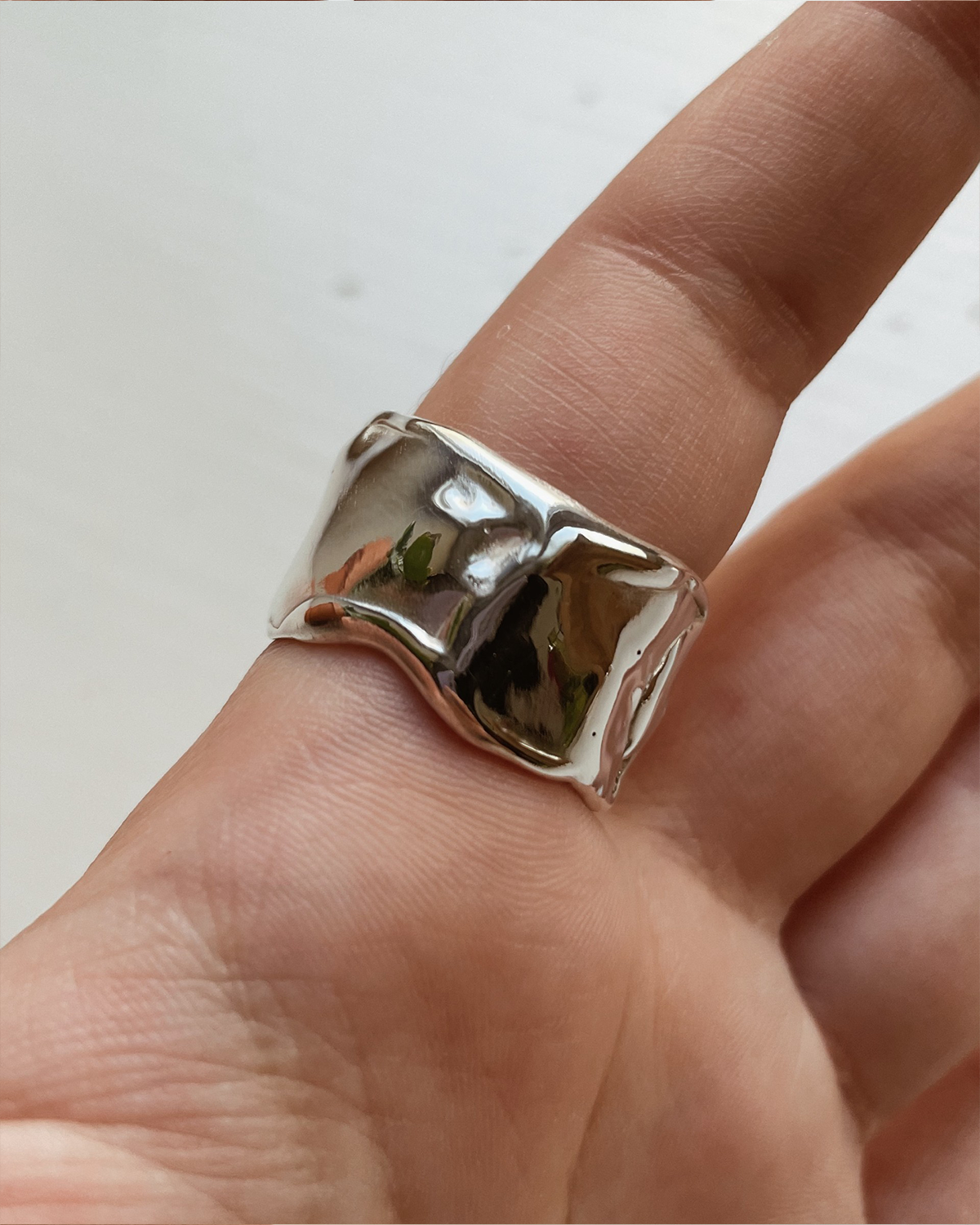 Silver ring on a finger against a neutral background