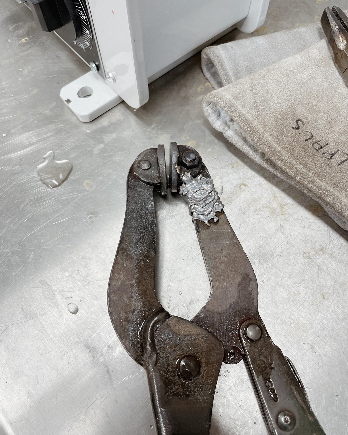 Metal pliers with a small object on a metallic surface