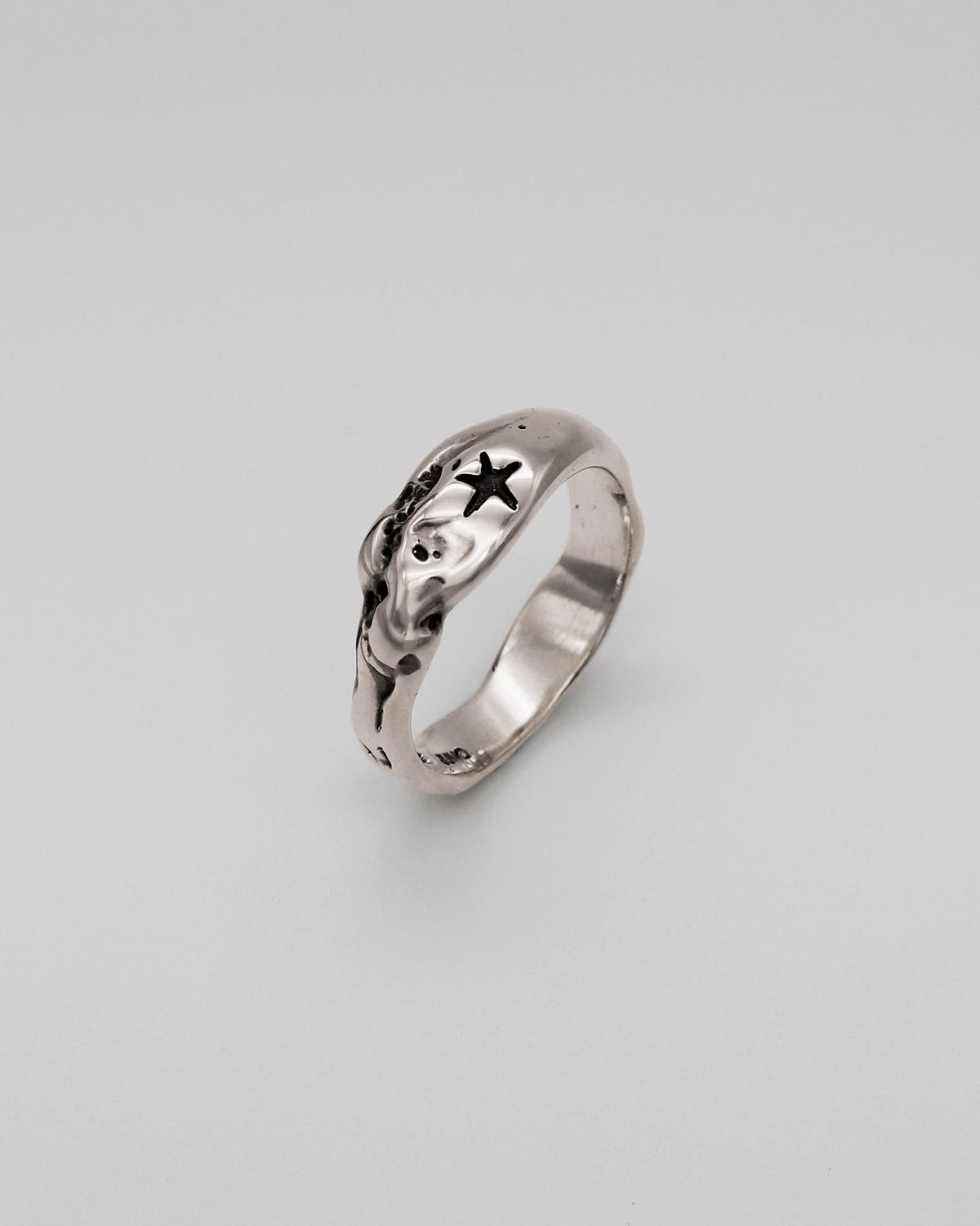 Silver ring with star design on a light gray background