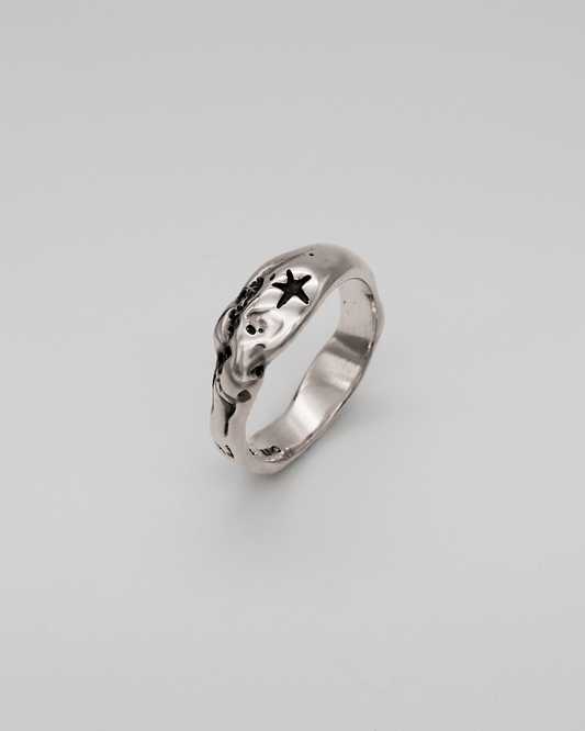 Silver ring with star design on a light gray background